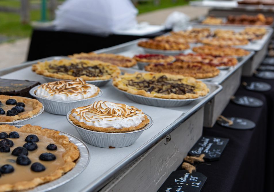Baked goods at outdoor agriculture fair. Homemade traditional tarts are seen displayed on a stall during a local farmer's market, sweet fruit pies and lemon meringues.