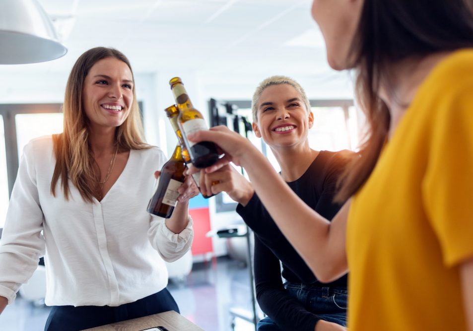 Shot,Of,Three,Young,Entrepreneur,Women,Toasting,With,A,Bottle Shot of three young entrepreneur women toasting with a bottle of beer to celebrate a success in the office.